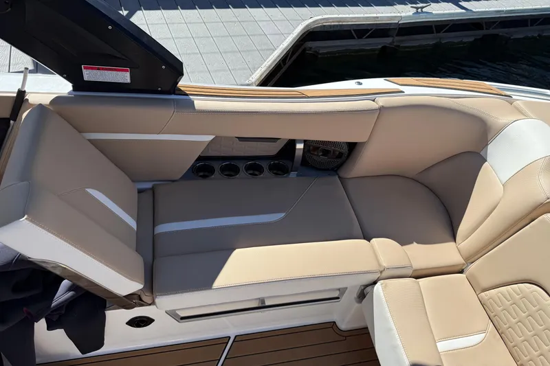 Slide: The Image of 2025 MasterCraft X24 boat interior with beige seating and cup holders. - 7