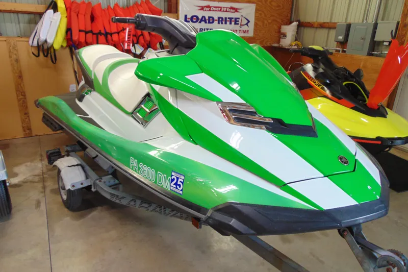 The Image of 2014 Yamaha WaveRunner FX HO in green and white, parked indoors on a trailer. - 1