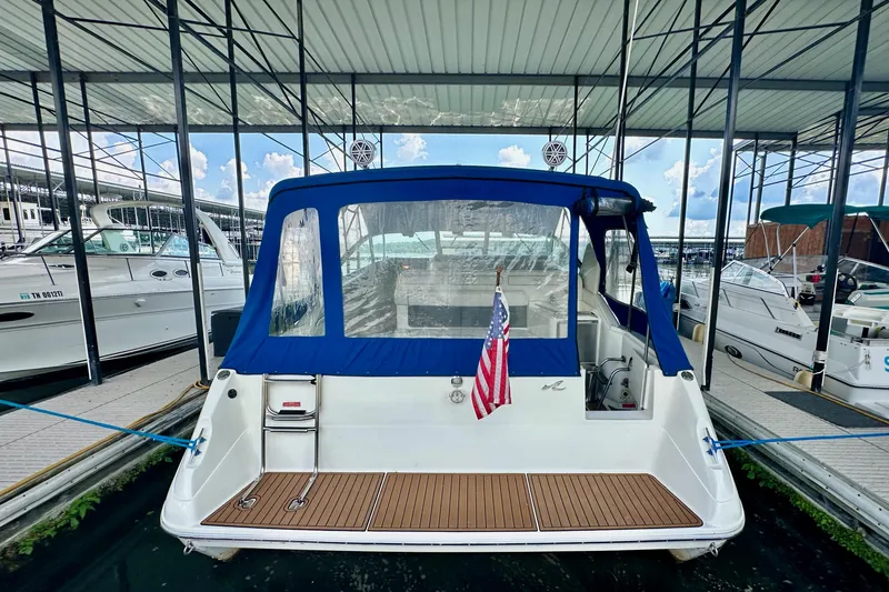 Slide: The Image of 1994 Sea Ray 330 Sundancer docked, featuring blue canopy and American flag. - 5
