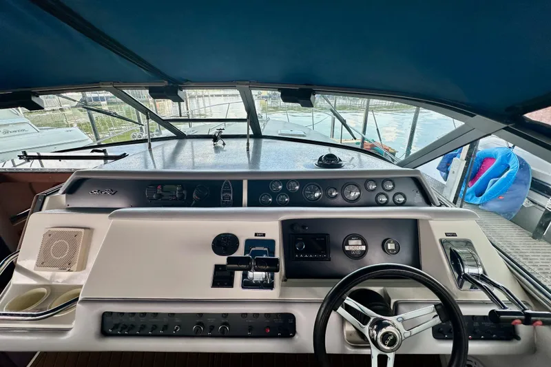 Slide: The Image of 1994 Sea Ray 330 Sundancer helm with steering wheel, gauges, and controls under a blue canopy. - 6