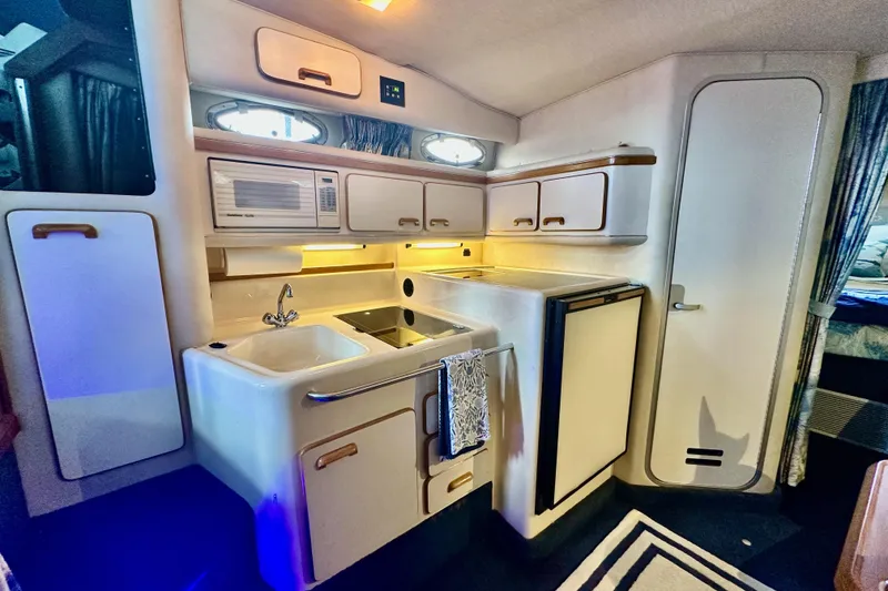 Slide: The Image of 1994 Sea Ray 330 Sundancer interior kitchen with sink, microwave, and storage cabinets. - 9