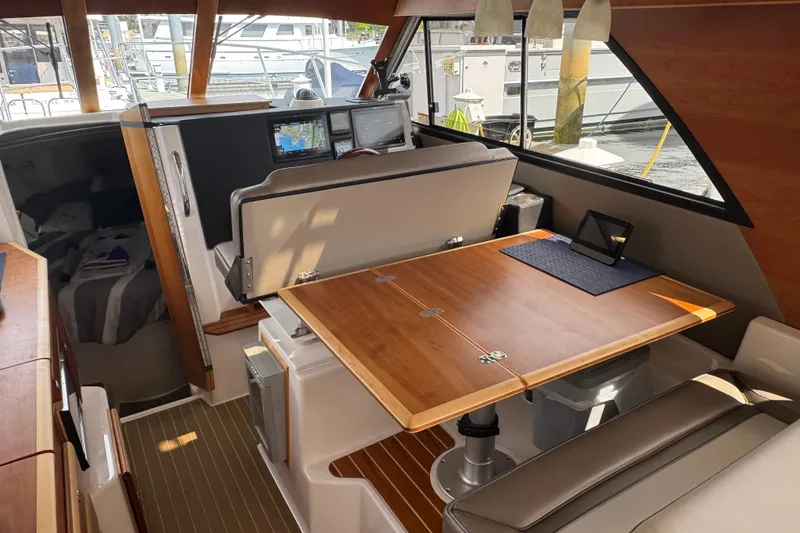Slide: The Image of 2020 Cutwater C-30 CB interior with wooden table, navigation screens, and cozy cabin space. - 16