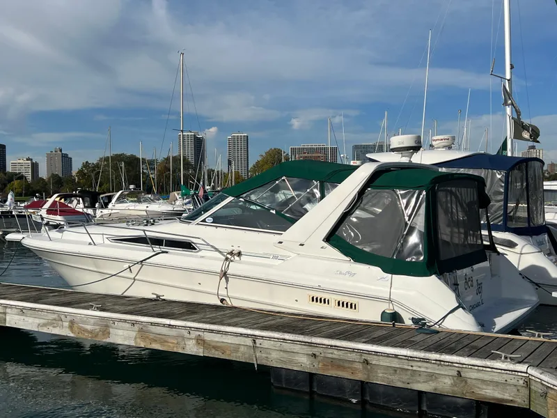 Slide: The Image of 1991 Sea Ray 310/330 Sundancer docked at a marina with city skyline in background. - 3