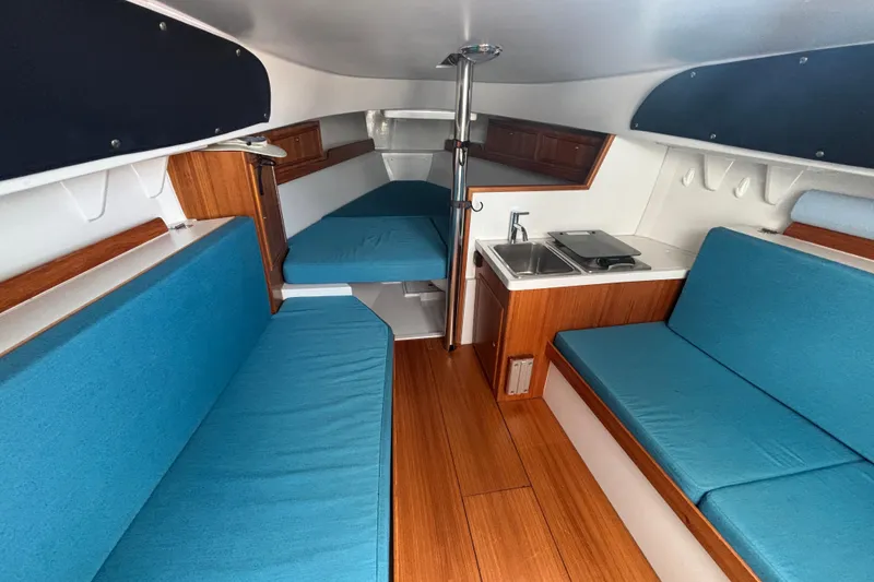 Slide: The Image of Interior of 2019 Saffier Sc 8.0m Cabin with blue seating and compact kitchenette. - 8
