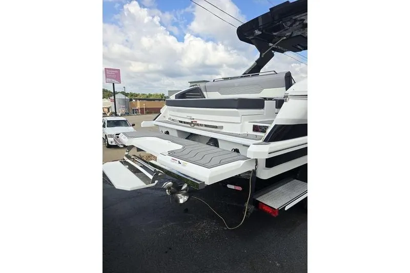 Slide: The Image of 2026 Cobalt A29 boat rear view with swim platform and seating, parked outdoors. - 12