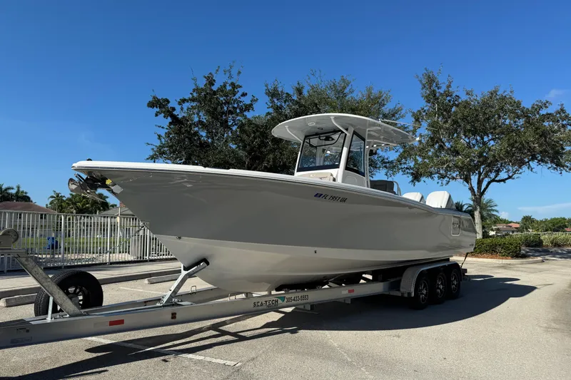 Slide: The Image of 2025 Sea Hunt Ultra 305 SE boat on trailer, parked outdoors under clear blue sky. - 2