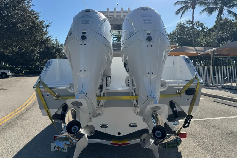 Slide: The Image of 2025 Sea Hunt Ultra 305 SE boat with dual outboard engines, parked on a sunny street. - 4