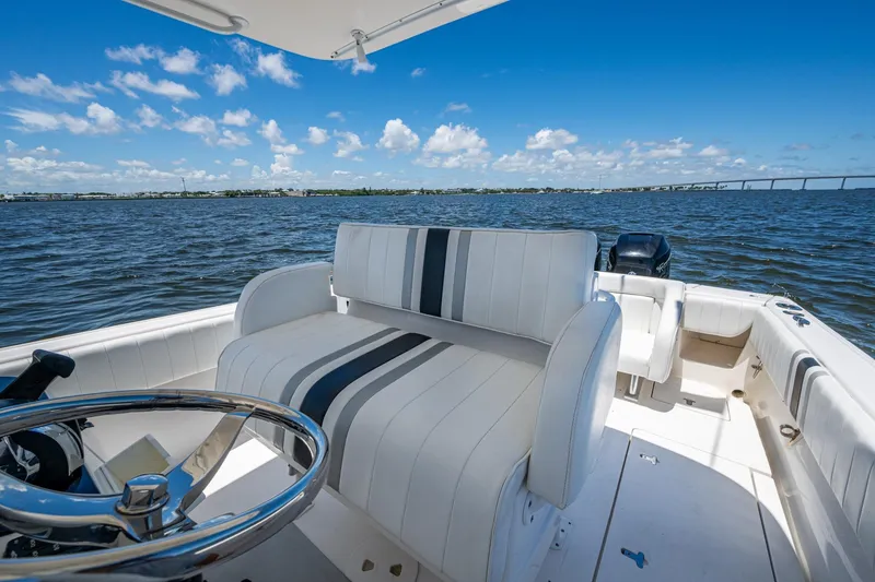 Slide: The Image of 2010 Intrepid 323 OPEN boat interior with striped seating on a sunny day. - 15