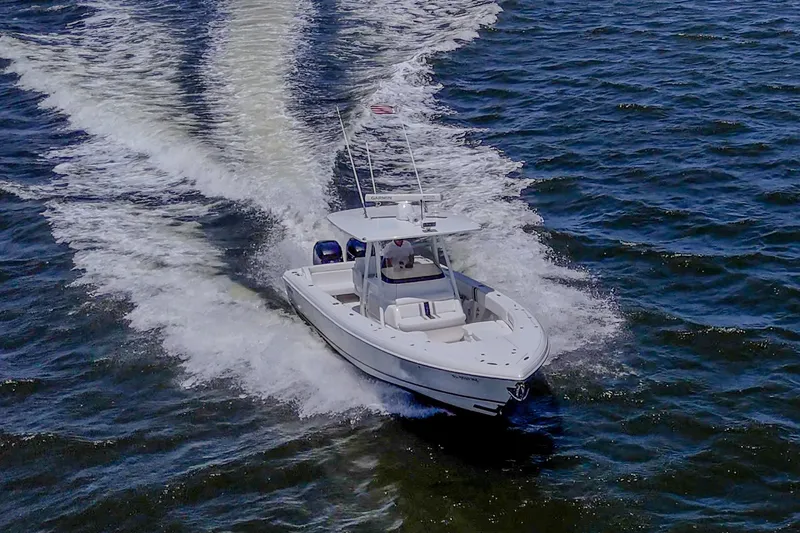 Slide: The Image of 2010 Intrepid 323 OPEN boat cruising on open water, creating a wake. - 2