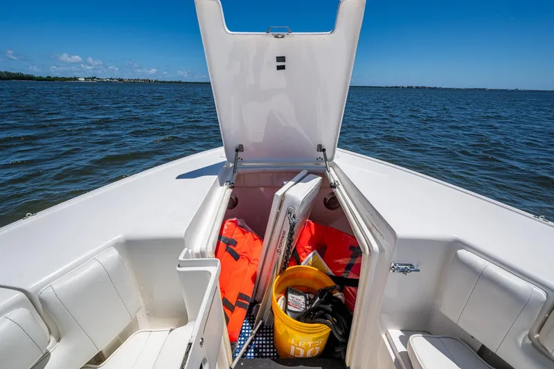 Slide: The Image of 2010 Intrepid 323 OPEN boat with open storage, life jackets, and safety gear on water. - 32