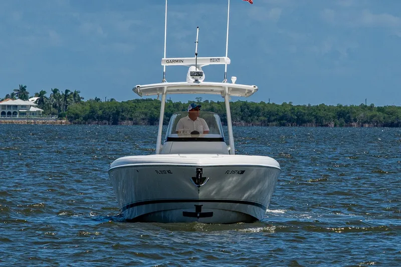 Slide: The Image of 2010 Intrepid 323 OPEN boat cruising on a sunny day with lush shoreline backdrop. - 8