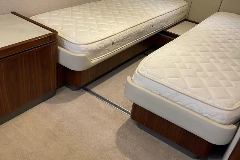 Slide: The Image of Twin beds in a 2020 Riviera 4800 Sport Yacht cabin with wooden accents. - 11
