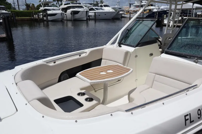Slide: The Image of 2017 Boston Whaler 270 Vantage boat interior with seating and table, docked near yachts. - 12