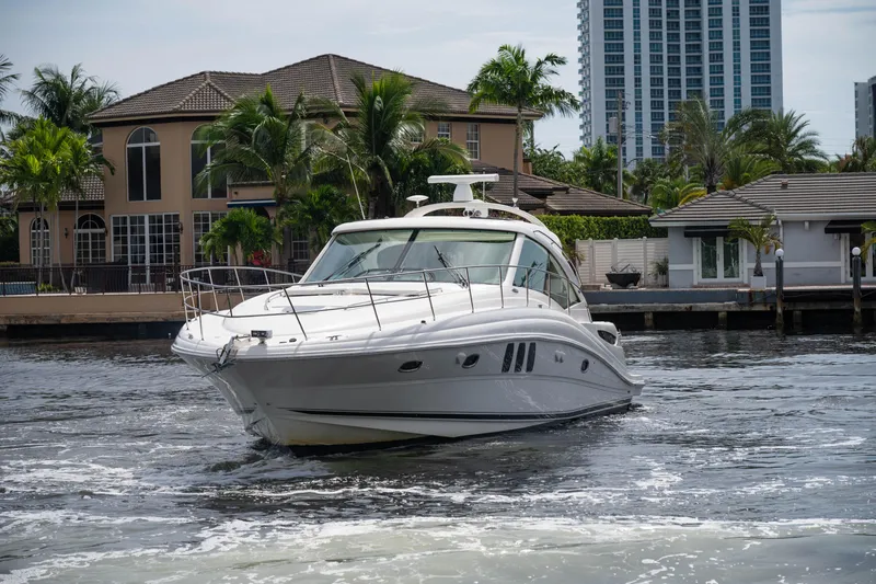 The Image of 2006 Sea Ray 48 Sundancer yacht cruising near waterfront homes and palm trees. - 0