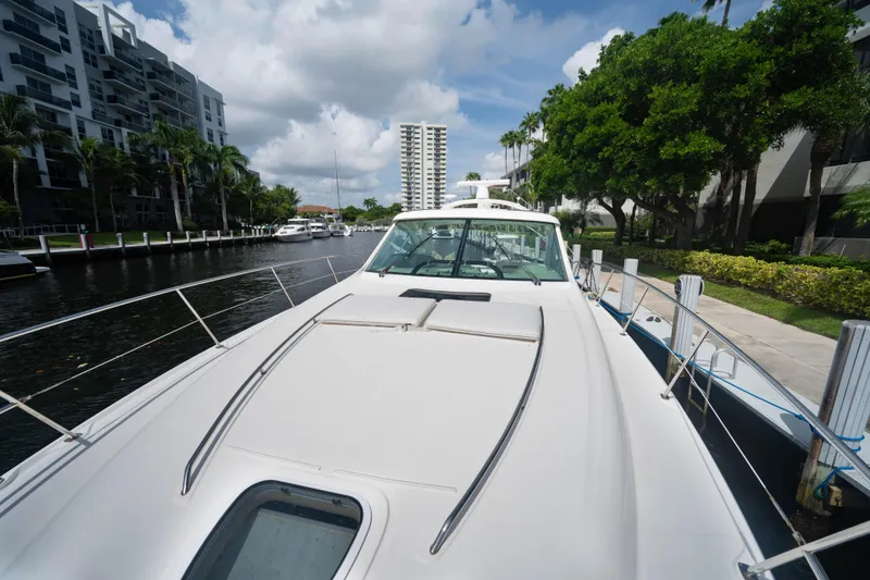 Slide: The Image of 2006 Sea Ray 48 Sundancer yacht docked by waterfront buildings and lush greenery. - 21