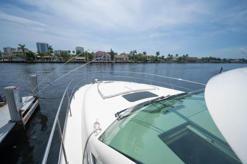 Slide: The Image of 2006 Sea Ray 48 Sundancer yacht docked by waterfront homes under a clear blue sky. - 23