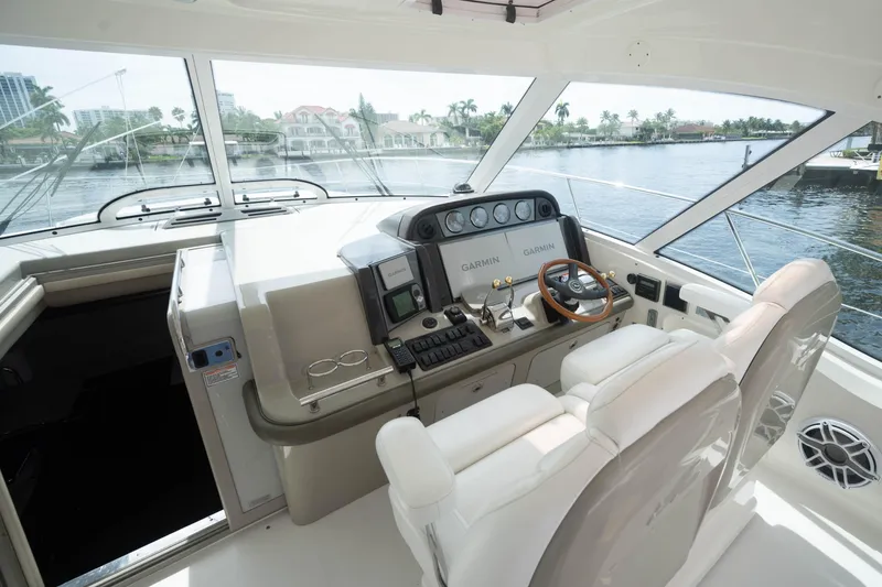 Slide: The Image of 2006 Sea Ray 48 Sundancer helm with Garmin navigation, luxurious seating, and waterfront view. - 9