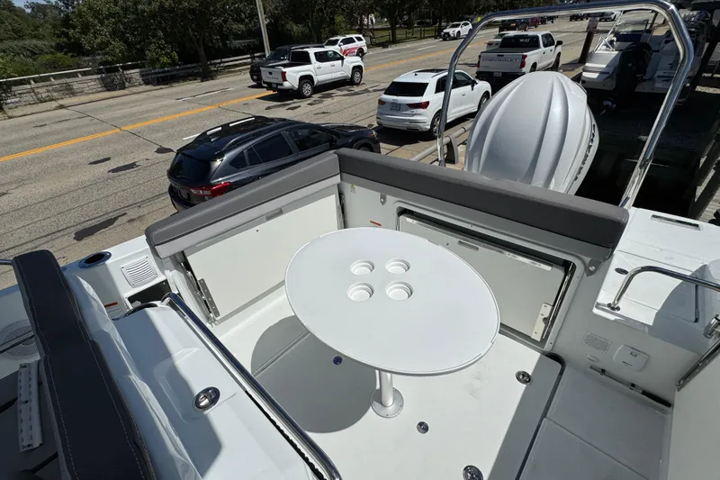 Slide: The Image of 2026 Jeanneau Leader WA 7.5 boat deck with seating and table, parked near road. - 10