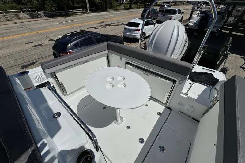 Slide: The Image of 2026 Jeanneau Leader WA 7.5 boat interior with seating and round table, docked near vehicles. - 11