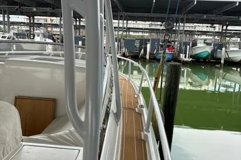 Slide: The Image of 2006 Intrepid 310 Walkaround boat docked in a marina, featuring a covered seating area. - 32