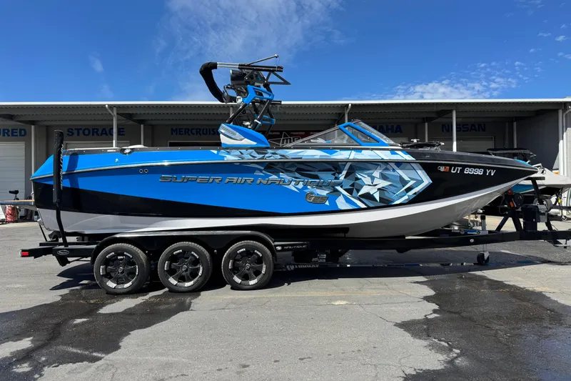 The Image of 2015 Nautique Super Air Nautique G25 boat in blue and black on a trailer. - 1