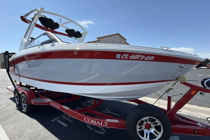 Slide: The Image of 2021 Cobalt R6 Surf boat on a red trailer, parked outdoors under a clear sky. - 10