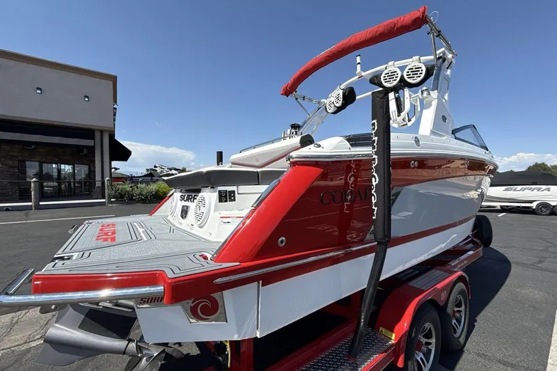Slide: The Image of 2021 Cobalt R6 Surf boat on trailer, red and white design, parked outdoors. - 8