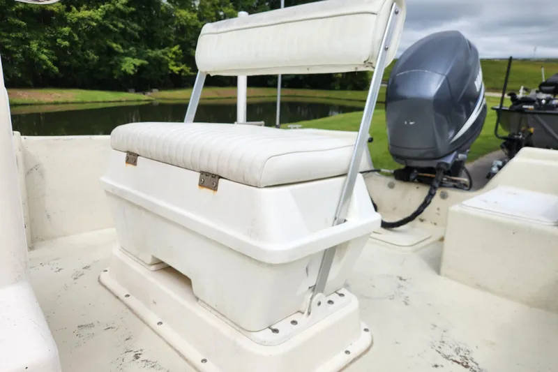 Slide: The Image of 2008 May-Craft 1800 Skiff boat with white seating and outboard motor, near a serene lake. - 11