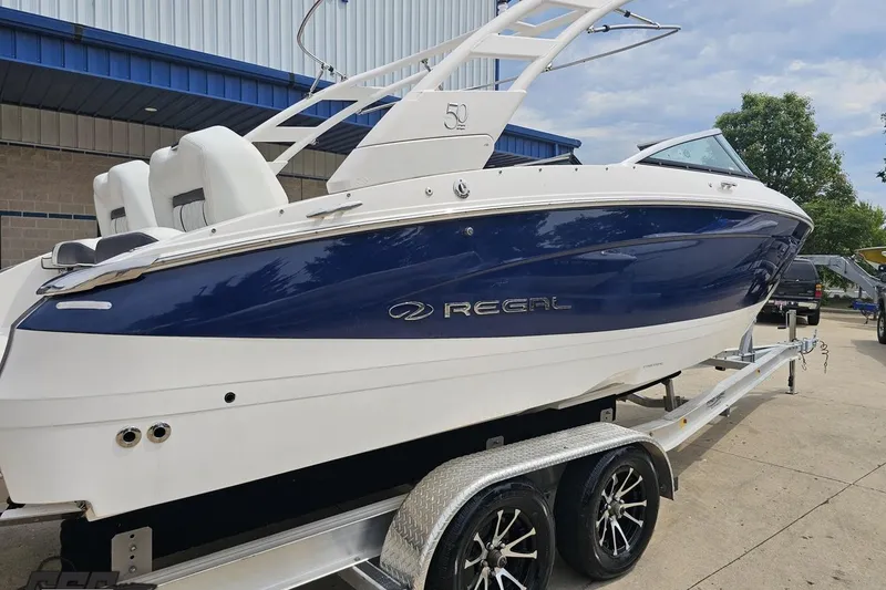 Slide: The Image of 2021 Regal LX4 boat on trailer, blue and white design, parked outdoors. - 10
