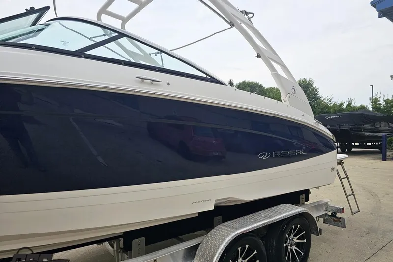 Slide: The Image of 2021 Regal LX4 boat on trailer, sleek design, navy and white exterior. - 23