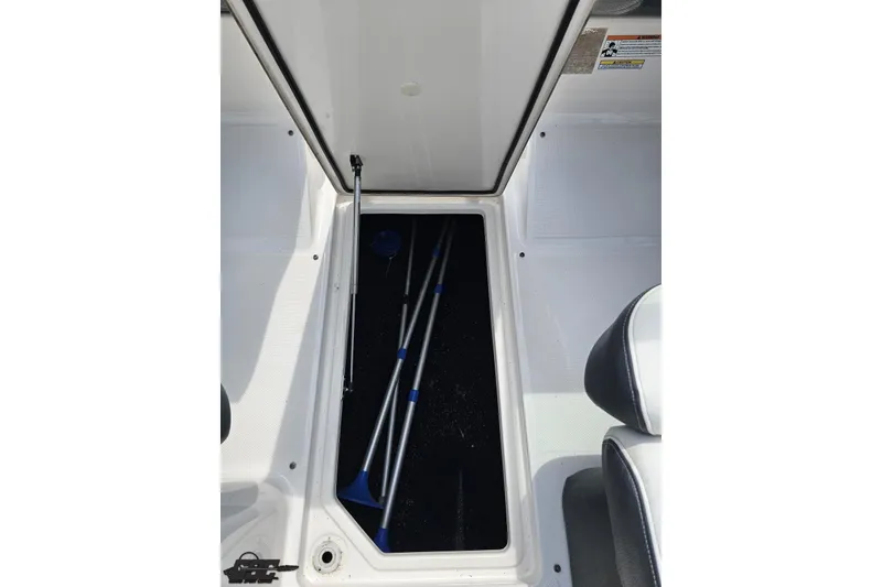 Slide: The Image of 2021 Regal LX4 boat storage compartment with open lid and equipment inside. - 59