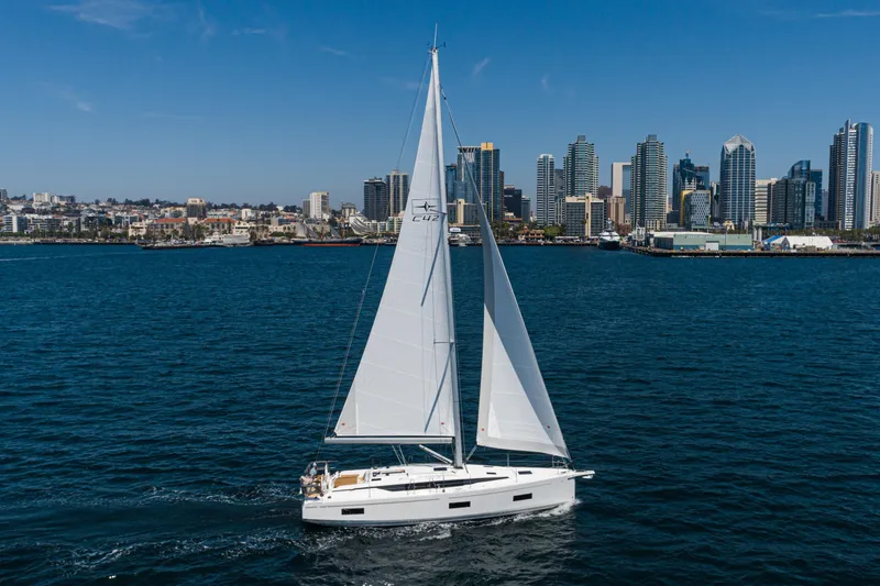 Slide: The Image of Sailing yacht Bavaria C42, 2023 model, cruising near a city skyline on a sunny day. - 13