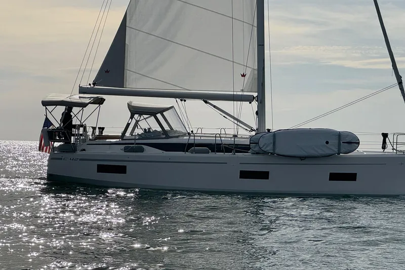 Slide: The Image of 2023 Bavaria C42 sailboat gliding on shimmering water under a clear sky. - 4