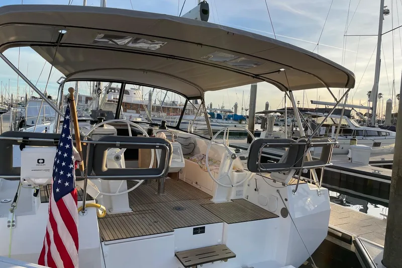 Slide: The Image of 2023 Bavaria C42 yacht docked at marina, featuring dual steering wheels and American flag. - 5