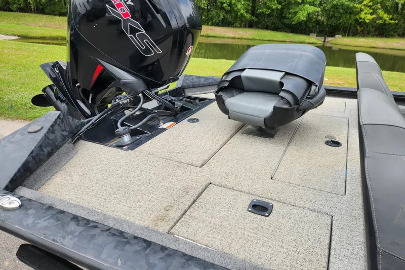 Slide: The Image of 2023 Tracker Pro Team 190 TX boat with motor and seating, near a serene pond. - 10