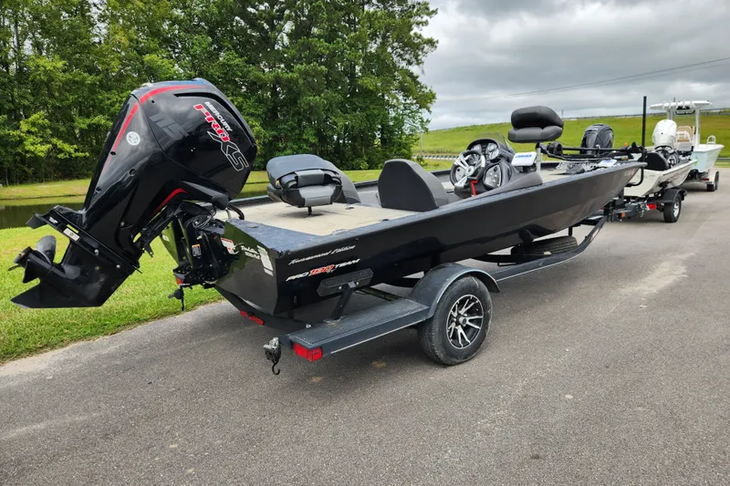 Slide: The Image of 2023 Tracker Pro Team 190 TX boat on trailer, parked near a grassy area. - 2