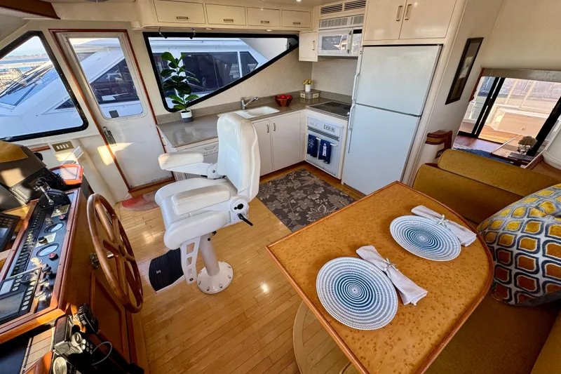 Slide: The Image of Luxurious 1995 Queenship 62 Pilothouse Motor Yacht interior with helm, kitchen, and dining area. - 12