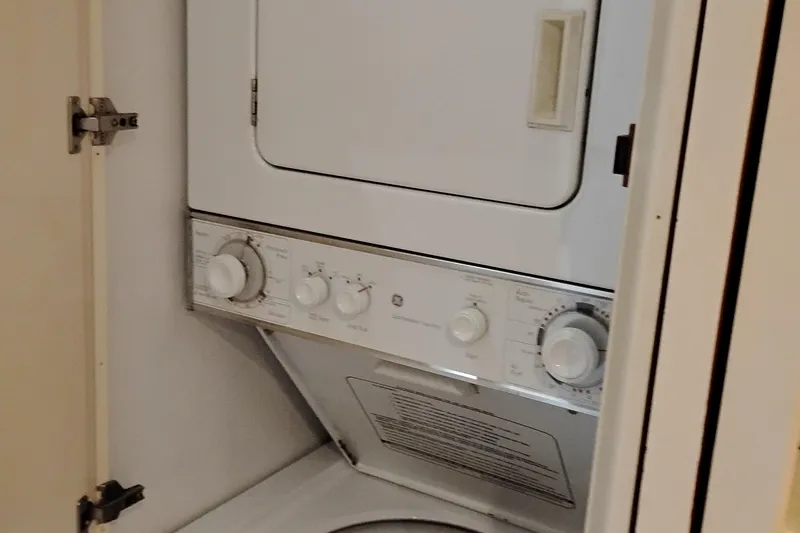 Slide: The Image of Laundry unit inside 1995 Queenship 62 Pilothouse Motor Yacht, featuring stacked washer and dryer. - 31