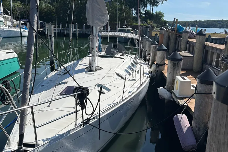 The Image of 1989 Beneteau First 41s5 sailboat docked at a marina, surrounded by calm water. - 0