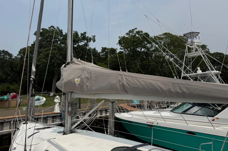 Slide: The Image of 1989 Beneteau First 41s5 sailboat docked, featuring covered mainsail and nearby motorboat. - 6