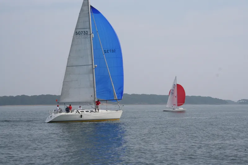 Slide: The Image of Sailboats on calm water, featuring a 1989 Beneteau First 41S5 with blue sails. - 37