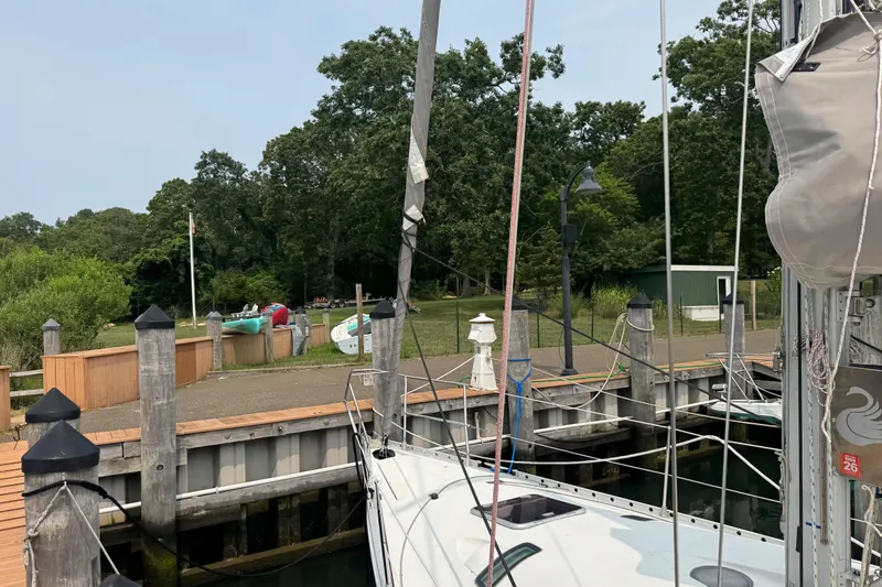 Slide: The Image of Beneteau First 41s5 sailboat docked at a marina, surrounded by lush greenery, 1989 model. - 5