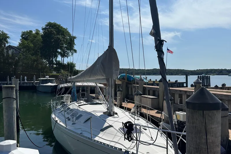 Slide: The Image of 1989 Beneteau First 41s5 sailboat docked at a scenic marina with clear skies. - 4
