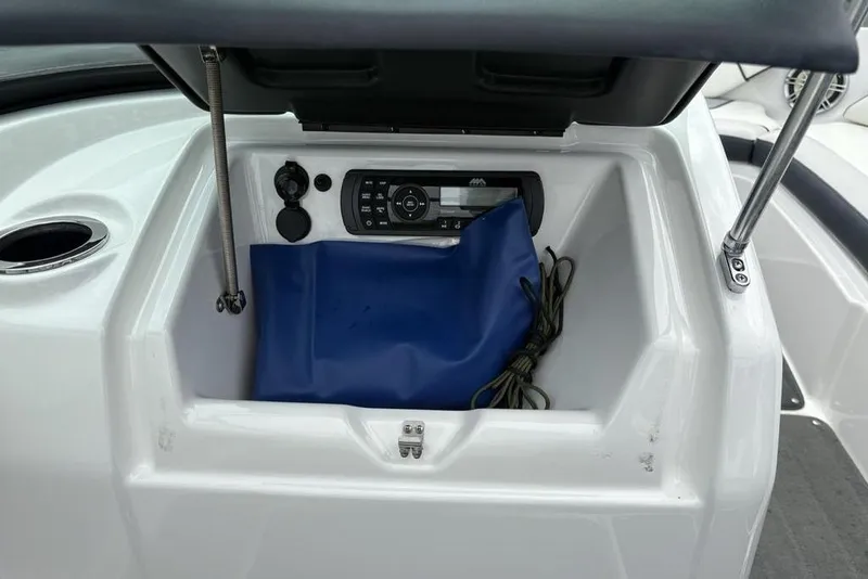 Slide: The Image of 2017 Yamaha Boats SX195 storage compartment with audio system and blue bag. - 21