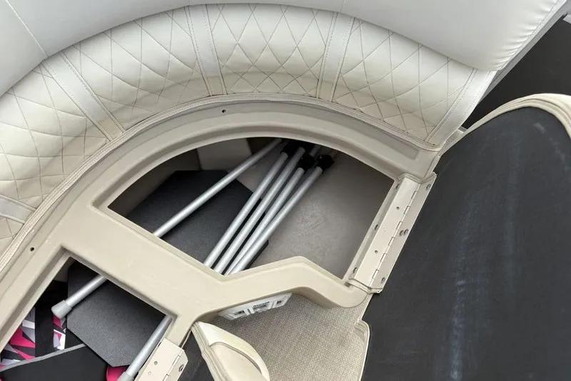 Slide: The Image of 2015 Bennington 24 S Series boat storage compartment with cushioned seating and metal poles. - 11