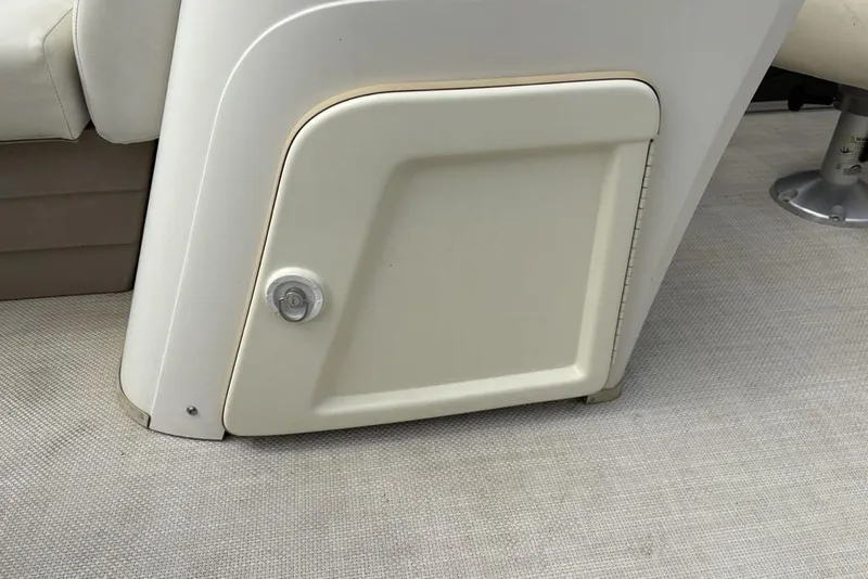 Slide: The Image of 2015 Bennington 24 S Series boat storage compartment with beige seating and carpeted floor. - 12