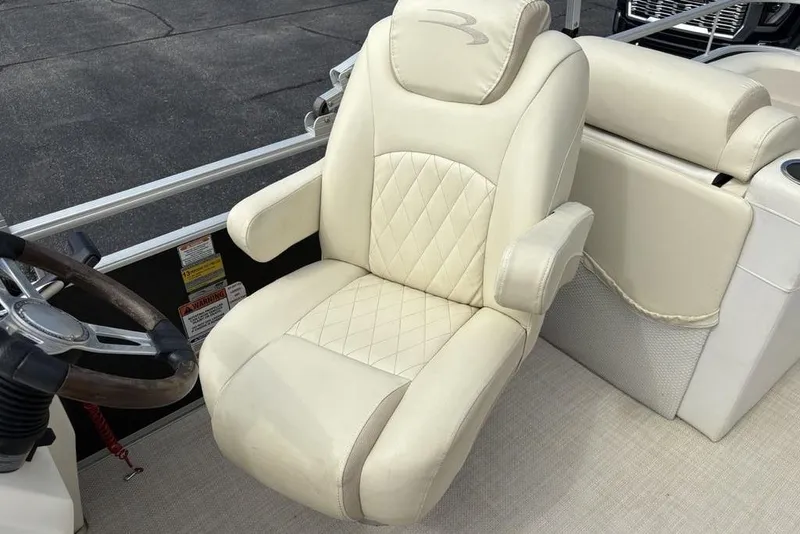 Slide: The Image of Captain's chair on 2015 Bennington 24 S Series pontoon boat, featuring beige upholstery and armrests. - 23