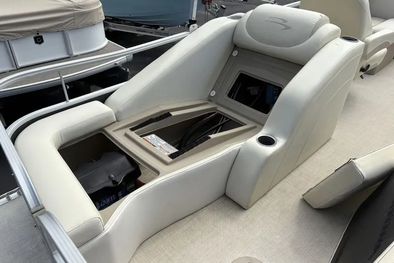 Slide: The Image of 2015 Bennington 24 S Series boat interior with open storage compartment and beige seating. - 25