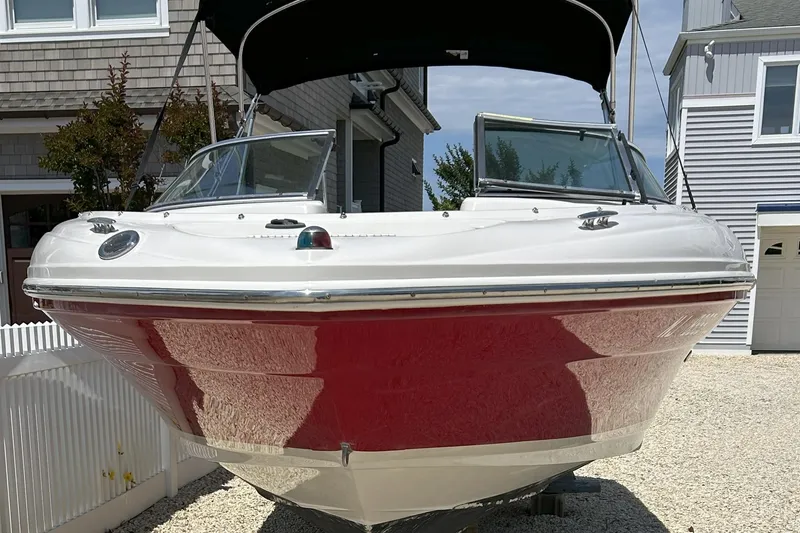 Slide: The Image of 2007 Sea Ray 205 Sport boat with red hull, parked in a residential driveway. - 6