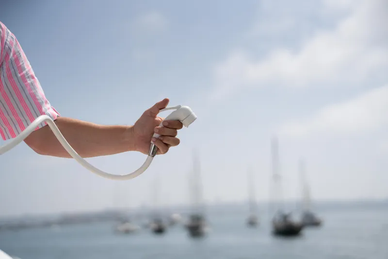 Slide: The Image of Hand holding a hose on a Tide Craft Galveston 19 boat, 2026, with sailboats in the background. - 13